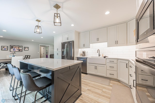 407 6th St NE, Barnesville, MN 56514 - kitchen featuring stainless steel appliances, a kitchen island, light countertops, decorative backsplash, and a breakfast bar