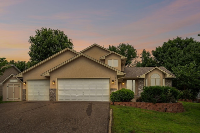 9055 Regent Pkwy, Brooklyn Park, MN 55443 - traditional-style home with an attached garage, driveway, stucco siding, and a lawn