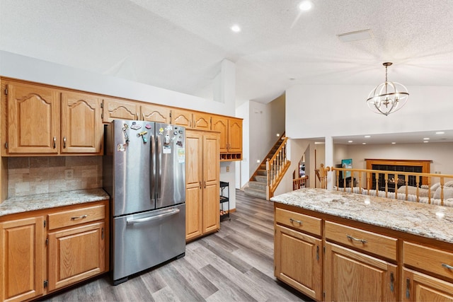 9055 Regent Pkwy, Brooklyn Park, MN 55443 - kitchen with freestanding refrigerator, vaulted ceiling, light wood-type flooring, decorative backsplash, and a chandelier
