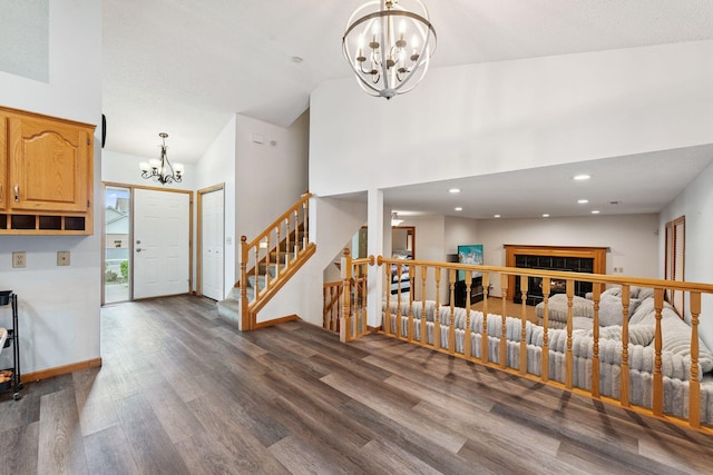 9055 Regent Pkwy, Brooklyn Park, MN 55443 - entrance foyer with a chandelier, dark wood-type flooring, stairs, a glass covered fireplace, and high vaulted ceiling