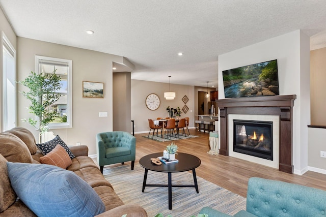 5053 Sunstream Ln, Woodbury, MN 55129 - living area with light wood-style floors, recessed lighting, a textured ceiling, and a glass covered fireplace