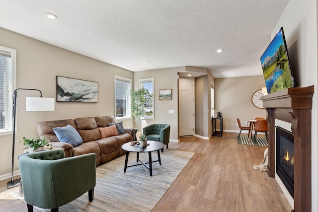 5053 Sunstream Ln, Woodbury, MN 55129 - living room featuring light wood-style floors, a glass covered fireplace, recessed lighting, and a textured ceiling