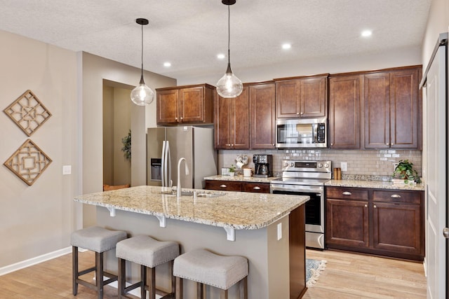 5053 Sunstream Ln, Woodbury, MN 55129 - kitchen featuring appliances with stainless steel finishes, light wood-type flooring, backsplash, a kitchen bar, and recessed lighting