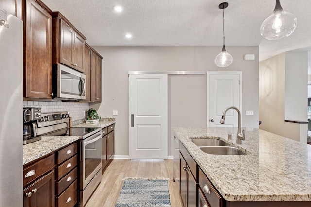 5053 Sunstream Ln, Woodbury, MN 55129 - kitchen with stainless steel appliances, an island with sink, light wood-style flooring, backsplash, and pendant lighting