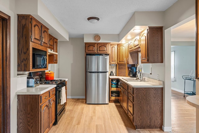 1062 Ohio St, West Saint Paul, MN 55118 - kitchen featuring black appliances, light wood-style floors, light countertops, under cabinet range hood, and a textured ceiling