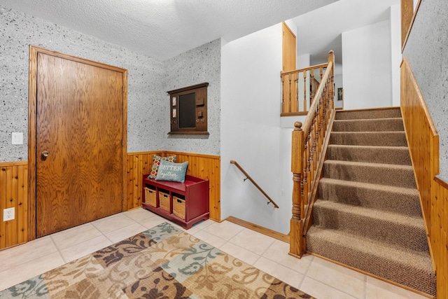 13326 Mallard Dr SE, Becker Twp, MN 55308 - foyer with wainscoting, wood walls, light tile patterned flooring, a textured ceiling, and stairs