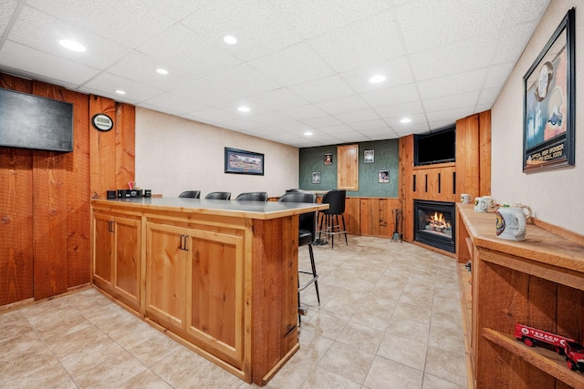 13326 Mallard Dr SE, Becker Twp, MN 55308 - kitchen with wooden walls, a glass covered fireplace, a peninsula, light countertops, and a kitchen breakfast bar
