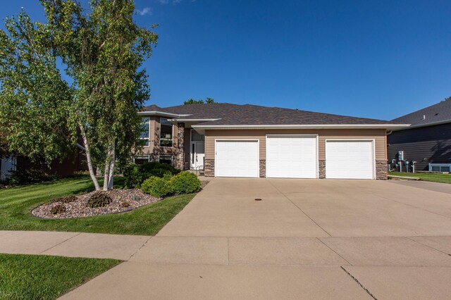 406 13th Ave NW, Kasson, MN 55944 - view of front of house featuring stone siding, concrete driveway, an attached garage, and a front yard