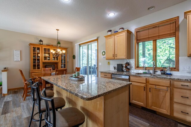 406 13th Ave NW, Kasson, MN 55944 - kitchen with backsplash, light brown cabinets, a kitchen bar, a chandelier, and a textured ceiling