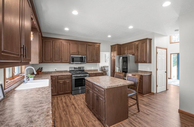 10695 184th Ave NW, Elk River, MN 55330 - kitchen with stainless steel appliances, dark wood finished floors, a kitchen island, a kitchen bar, and recessed lighting