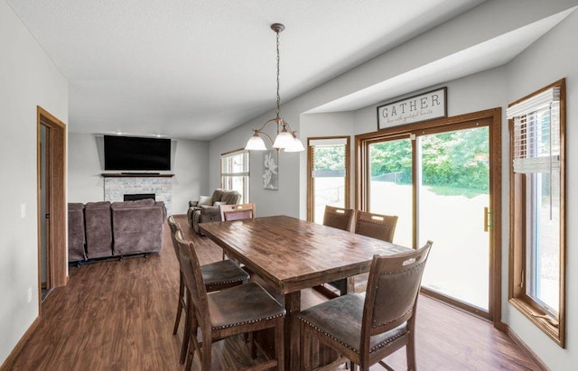10695 184th Ave NW, Elk River, MN 55330 - dining room with dark wood-type flooring, a stone fireplace, and a chandelier