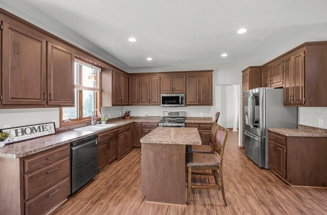 10695 184th Ave NW, Elk River, MN 55330 - kitchen featuring appliances with stainless steel finishes, a center island, wood finished floors, a breakfast bar area, and recessed lighting