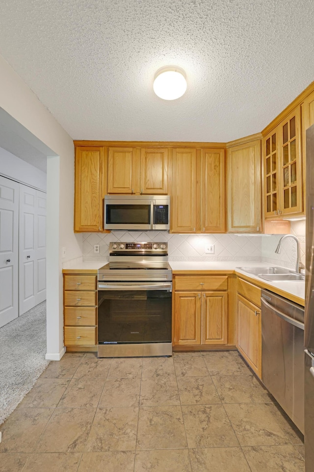 5643 Green Circle Dr Unit 107, Minnetonka, MN 55343 - kitchen with appliances with stainless steel finishes, light countertops, tasteful backsplash, glass insert cabinets, and a textured ceiling