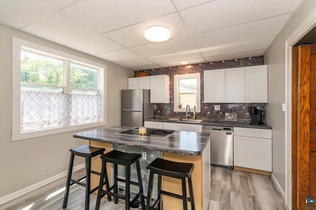 2014 5th St, Superior, WI 54880 - kitchen featuring appliances with stainless steel finishes, dark countertops, a drop ceiling, tasteful backsplash, and a kitchen bar