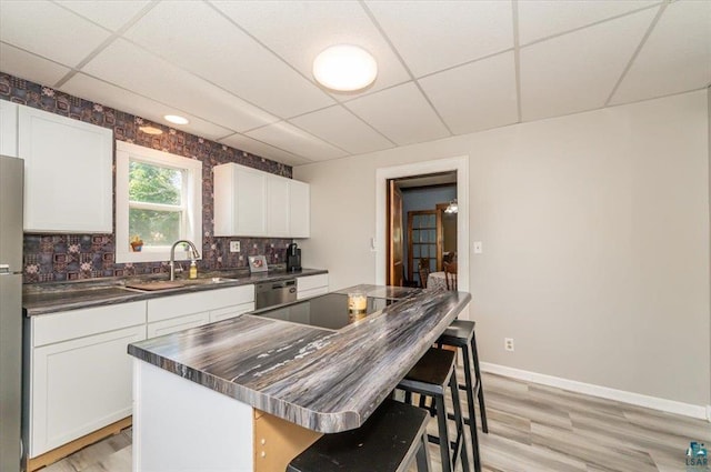 2014 5th St, Superior, WI 54880 - kitchen with a paneled ceiling, dark countertops, stainless steel dishwasher, a breakfast bar area, and light wood-style flooring