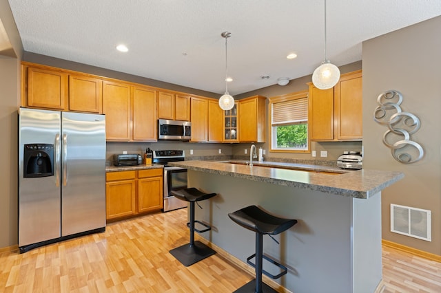 9605 Scott Cir N, Brooklyn Park, MN 55443 - kitchen featuring stainless steel appliances, light wood-style floors, a breakfast bar, glass insert cabinets, and recessed lighting
