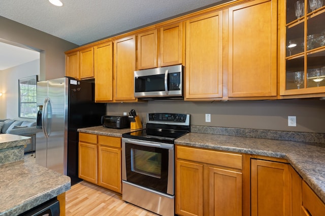 9605 Scott Cir N, Brooklyn Park, MN 55443 - kitchen featuring stainless steel appliances, light wood-style flooring, glass insert cabinets, and brown cabinets