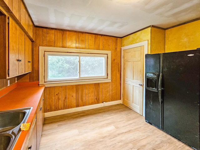 30867 Rasmussen Rd, Pequot Lakes, MN 56472 - kitchen featuring black fridge, light wood finished floors, brown cabinets, and wooden walls