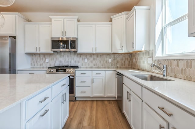 2550 Downing Ave, Shakopee, MN 55379 - kitchen with appliances with stainless steel finishes, white cabinets, light wood finished floors, and backsplash
