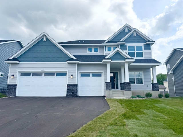 2550 Downing Ave, Shakopee, MN 55379 - craftsman-style home with asphalt driveway, stone siding, a front yard, and covered porch