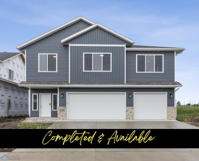 1057 61st Ave W, West Fargo, ND 58078 - view of property featuring an attached garage, concrete driveway, board and batten siding, and brick siding