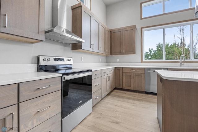 1057 61st Ave W, West Fargo, ND 58078 - kitchen featuring appliances with stainless steel finishes, wall chimney exhaust hood, light wood finished floors, and light countertops