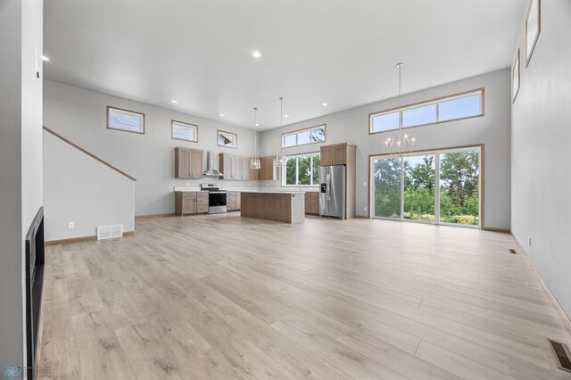 1057 61st Ave W, West Fargo, ND 58078 - unfurnished living room featuring a chandelier, light wood-style floors, recessed lighting, and a towering ceiling