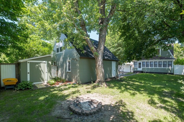 433 S Ave, North Mankato, MN 56003 - view of grassy yard featuring an outdoor fire pit, a storage shed, and a sunroom