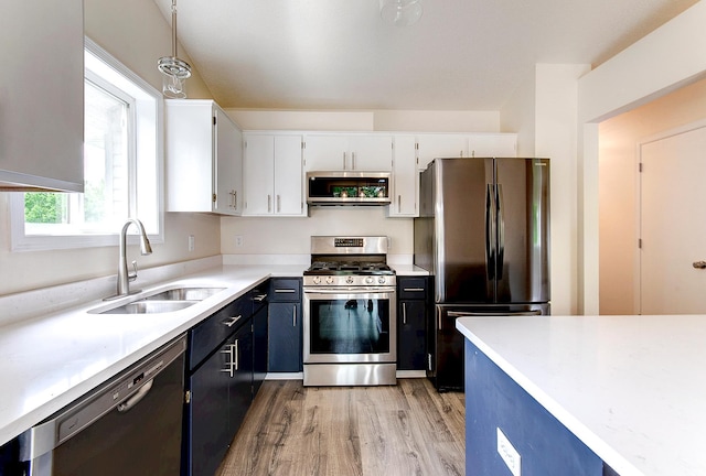 775 Leon St, Jordan, MN 55352 - kitchen featuring appliances with stainless steel finishes, light countertops, white cabinets, light wood-style flooring, and hanging light fixtures