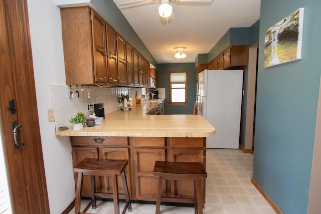 624 Garfield Ave, North Mankato, MN 56003 - kitchen featuring freestanding refrigerator, a peninsula, light countertops, light floors, and tasteful backsplash