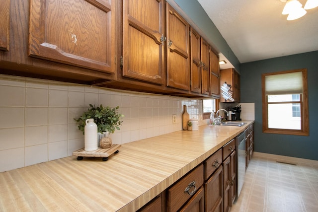 624 Garfield Ave, North Mankato, MN 56003 - kitchen with brown cabinets, stainless steel dishwasher, backsplash, and light countertops