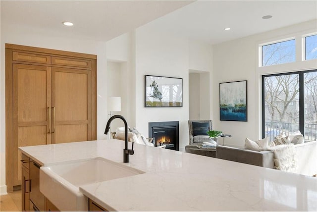 13975 27th St N, West Lakeland Twp, MN 55082 - kitchen featuring open floor plan, a glass covered fireplace, light stone countertops, recessed lighting, and light wood-style flooring