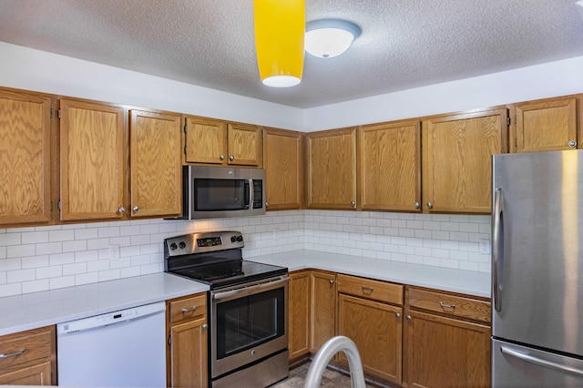 7639 Nicholas Way, Chanhassen, MN 55317 - kitchen featuring stainless steel appliances, light countertops, brown cabinetry, and a textured ceiling