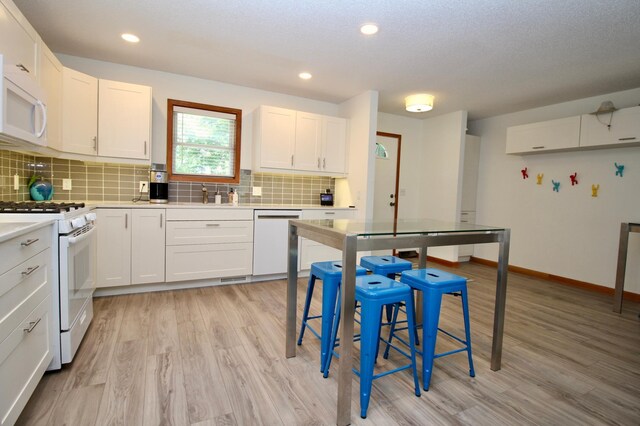 11715 Sorenson Lake Rd, Merrifield, MN 56465 - kitchen with white appliances, light wood-style flooring, decorative backsplash, light countertops, and recessed lighting