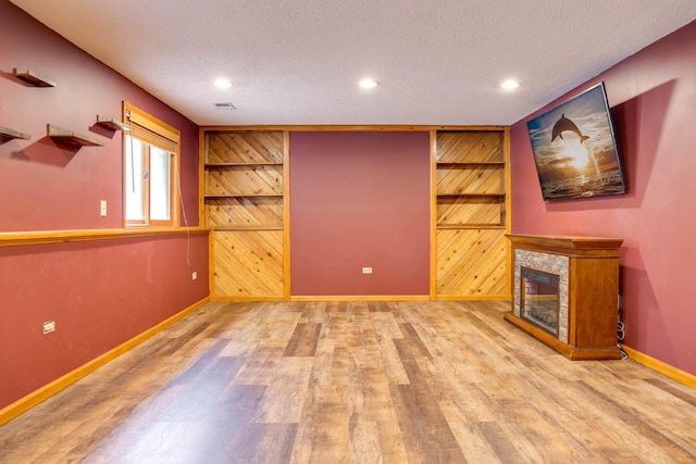 7771 Odean Ave NE, Otsego, MN 55330 - unfurnished living room featuring wooden walls, wood finished floors, recessed lighting, a textured ceiling, and a tile fireplace