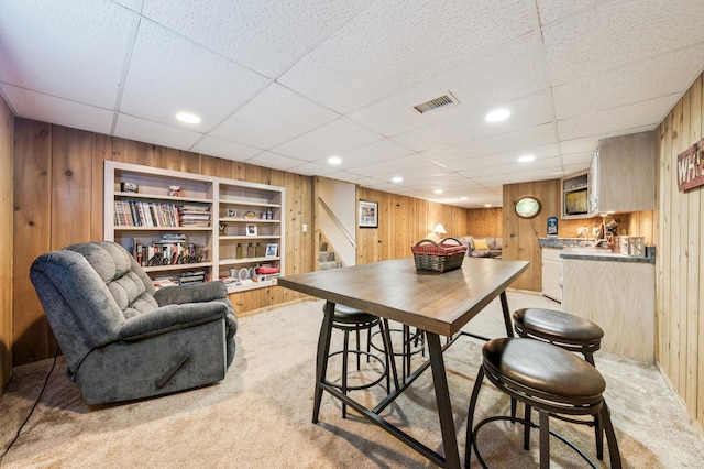 1073 Allen Ave W, Saint Paul, MN 55118 - dining area with light carpet, wooden walls, stairs, and a drop ceiling