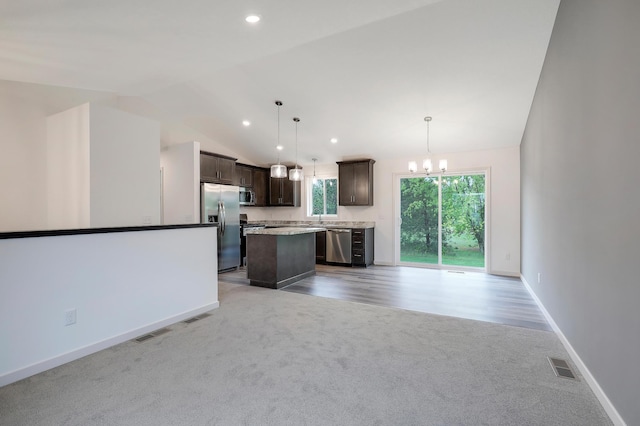 37554 Greenwich Ct, North Branch, MN 55056 - kitchen with appliances with stainless steel finishes, light colored carpet, dark brown cabinetry, a kitchen island, and a chandelier