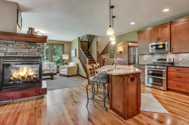 860 Prairie Meadows Dr, Hudson, WI 54016 - kitchen with stainless steel appliances, a stone fireplace, open floor plan, light wood-type flooring, and recessed lighting