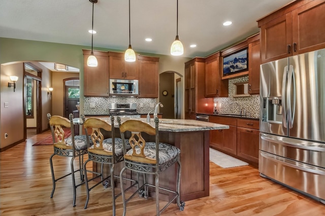 860 Prairie Meadows Dr, Hudson, WI 54016 - kitchen featuring appliances with stainless steel finishes, arched walkways, a kitchen bar, decorative backsplash, and recessed lighting