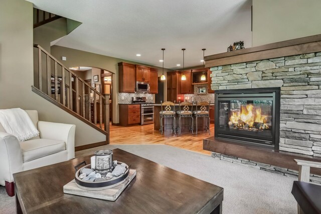 860 Prairie Meadows Dr, Hudson, WI 54016 - living room featuring arched walkways, stairway, a stone fireplace, recessed lighting, and light wood-style flooring