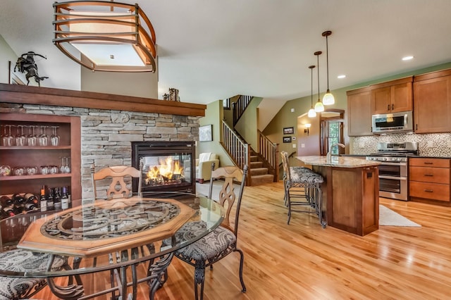 860 Prairie Meadows Dr, Hudson, WI 54016 - kitchen with stainless steel appliances, light wood-style flooring, light stone countertops, decorative backsplash, and a stone fireplace
