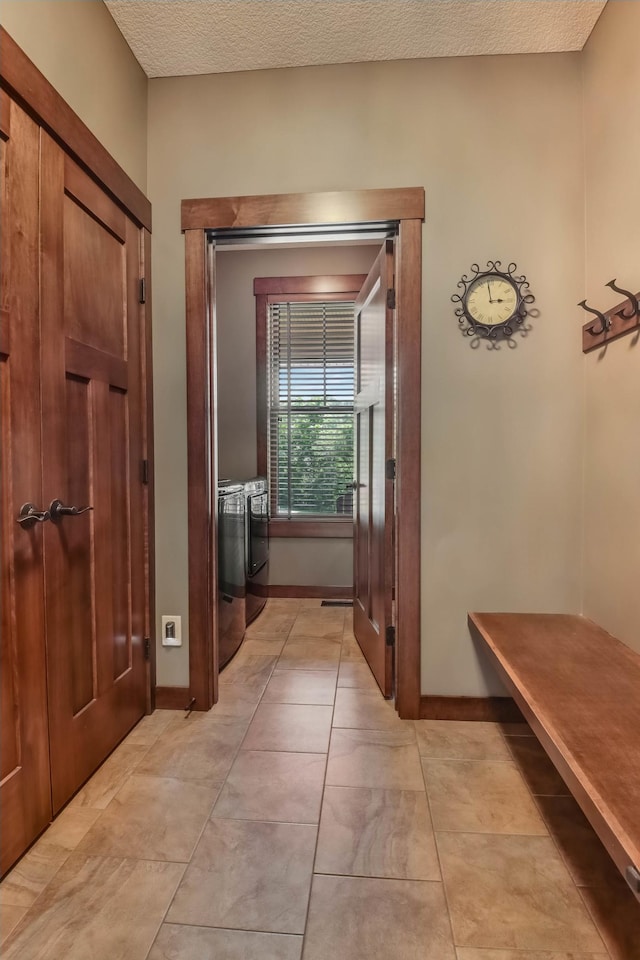 860 Prairie Meadows Dr, Hudson, WI 54016 - hallway featuring independent washer and dryer, a textured ceiling, and light tile patterned flooring