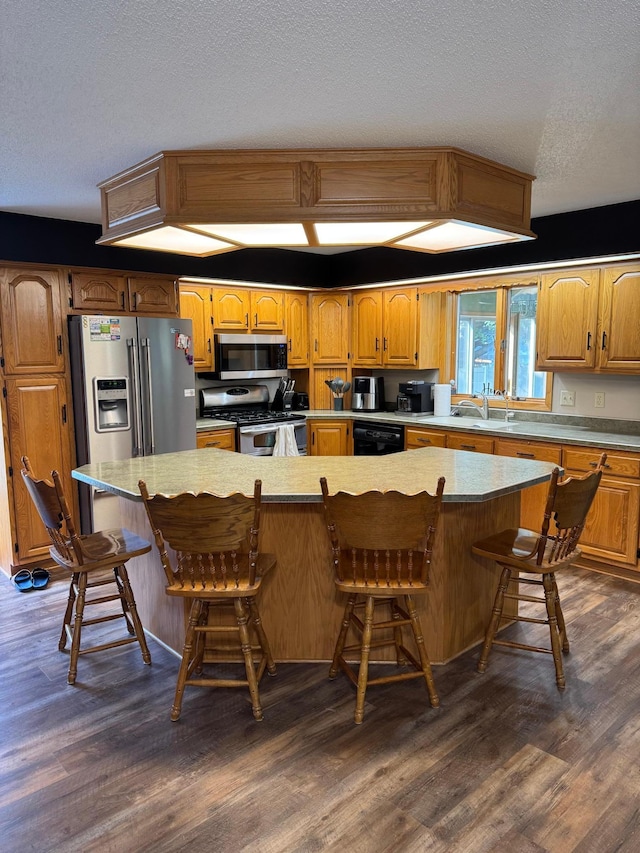 121 Park St, Luverne, MN 56156 - kitchen featuring stainless steel appliances, dark wood-style flooring, a textured ceiling, a breakfast bar, and a large island