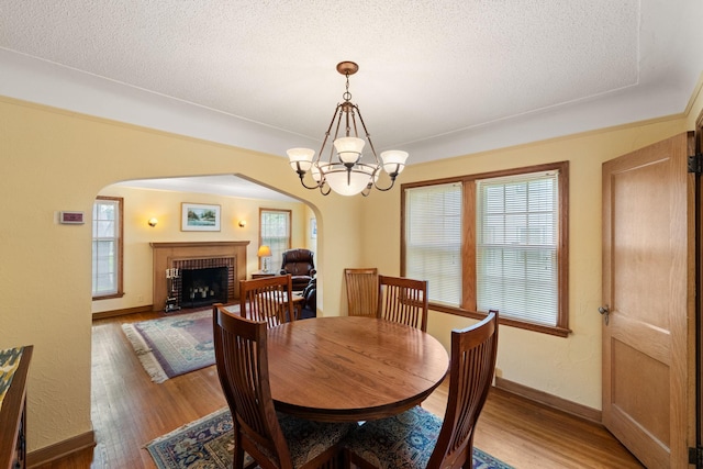 5924 10th Ave S, Minneapolis, MN 55417 - dining area featuring arched walkways, a fireplace, light wood-style flooring, a textured ceiling, and healthy amount of natural light