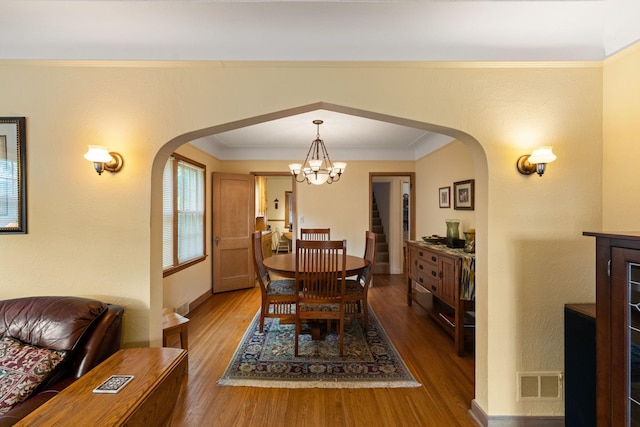 5924 10th Ave S, Minneapolis, MN 55417 - dining space featuring arched walkways, a chandelier, wood finished floors, stairs, and ornamental molding