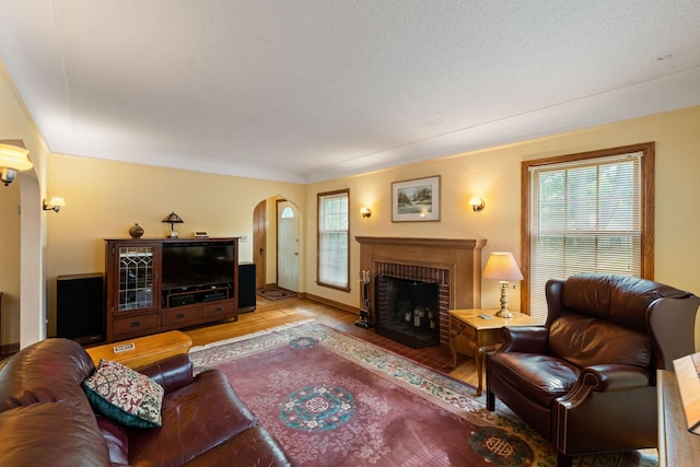 5924 10th Ave S, Minneapolis, MN 55417 - living room with arched walkways, wood finished floors, a brick fireplace, and crown molding