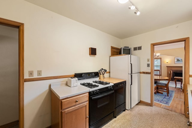 5924 10th Ave S, Minneapolis, MN 55417 - kitchen with range with gas stovetop, dishwasher, freestanding refrigerator, light countertops, and brown cabinetry