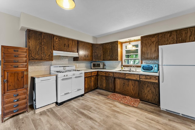 27900 Old Towne Rd, Chisago City, MN 55013 - kitchen featuring white appliances, under cabinet range hood, light wood-type flooring, light countertops, and decorative backsplash