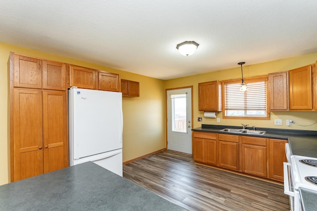 4540 Prairie View Pl NW, Rochester, MN 55901 - kitchen featuring white appliances, wood finished floors, dark countertops, hanging light fixtures, and brown cabinetry