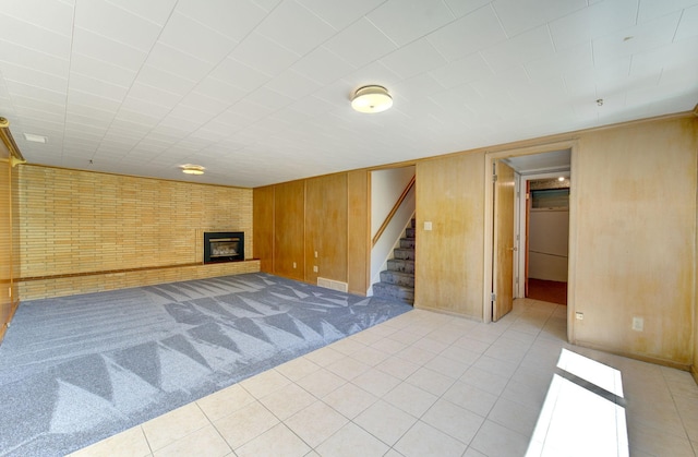 1636 9th Ave NE, Rochester, MN 55906 - finished basement featuring stairway, a glass covered fireplace, wooden walls, light carpet, and light tile patterned flooring